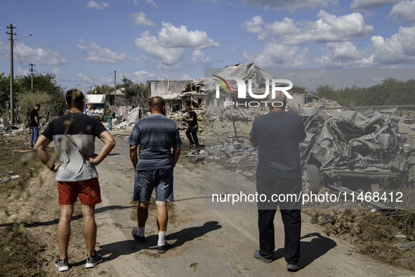 Local residents are standing next to a residential building in a village in the Kyiv region, heavily damaged during a massive Russian missil...