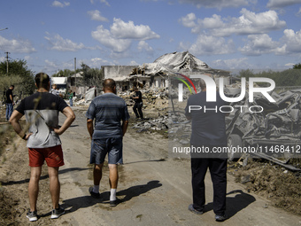 Local residents are standing next to a residential building in a village in the Kyiv region, heavily damaged during a massive Russian missil...