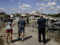 Local residents are standing next to a residential building in a village in the Kyiv region, heavily damaged during a massive Russian missil...