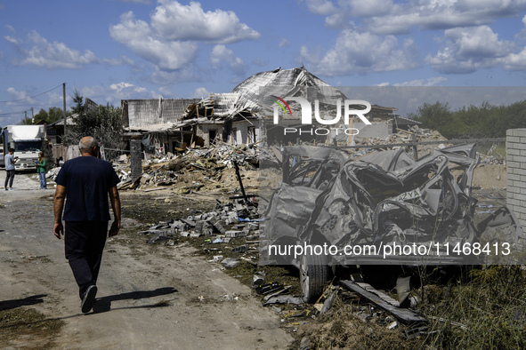 A local resident is standing next to a residential building in a village in the Kyiv region, heavily damaged during a massive Russian missil...