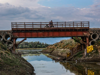 A biker is moving over an iron bridge as the level of water bodies has decreased, leaving boats on the shores and triggering a drought-like...