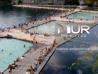 People refresh and sunbathe during a sunset of warm evening in Zakrzowek, a popular resort in Krakow, Poland on August 11, 2024. According t...