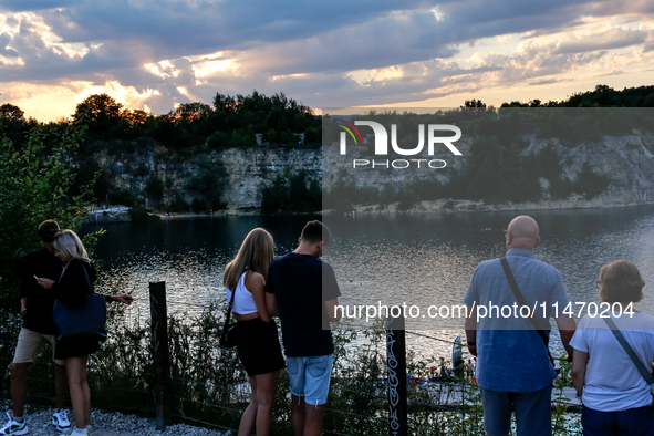 People watch a sunset during a warm evening in Zakrzowek, a popular resort in Krakow, Poland on August 11, 2024. According to the EU's clima...