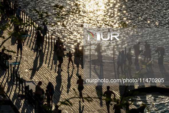 People refresh and sunbathe during a sunset of warm evening in Zakrzowek, a popular resort in Krakow, Poland on August 11, 2024. According t...