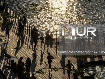 People refresh and sunbathe during a sunset of warm evening in Zakrzowek, a popular resort in Krakow, Poland on August 11, 2024. According t...