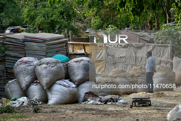 A man is standing by sacks containing paper scraps to be recycled outside a paper and cardboard recycling facility in Haldwani, Uttarakhand,...