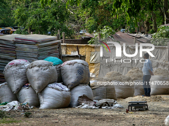 A man is standing by sacks containing paper scraps to be recycled outside a paper and cardboard recycling facility in Haldwani, Uttarakhand,...