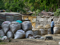 A man is standing by sacks containing paper scraps to be recycled outside a paper and cardboard recycling facility in Haldwani, Uttarakhand,...