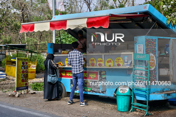 People are ordering food at a food cart along the roadside in Haldwani, Uttarakhand, India, on April 23, 2024. 