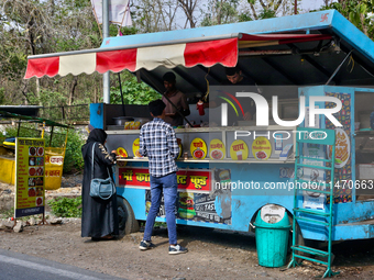 People are ordering food at a food cart along the roadside in Haldwani, Uttarakhand, India, on April 23, 2024. (