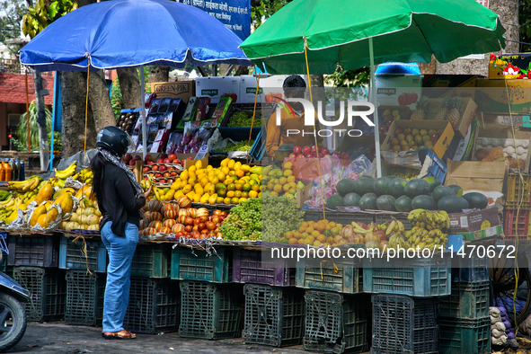 A woman is buying fresh fruit at a fruit stand along the roadside in Haldwani, Uttarakhand, India, on April 23, 2024. 