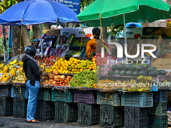 A woman is buying fresh fruit at a fruit stand along the roadside in Haldwani, Uttarakhand, India, on April 23, 2024. (