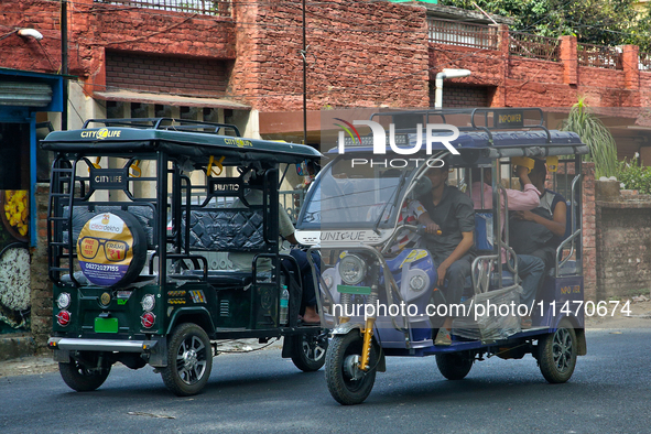 Auto-rickshaws are traveling along the road in Haldwani, Uttarakhand, India, on April 23, 2024. 