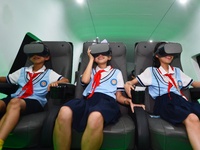 Primary school children are experiencing a VR4D image of high-speed rail at the Jiaoji Railway Museum in Qingdao, Shandong province, China,...