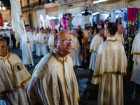 A member of the confraternity is participating in the procession of the statue of the Three Saints of Bisceglie among the stalls set up for...