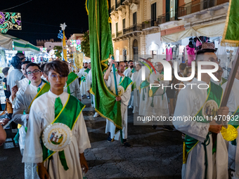 Members of the confraternity are processing the statue of the Three Saints of Bisceglie among the stalls set up for the festival in the town...