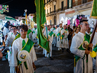 Members of the confraternity are processing the statue of the Three Saints of Bisceglie among the stalls set up for the festival in the town...