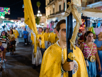 A member of the confraternity is participating in the procession of the statue of the Three Saints of Bisceglie among the stalls set up for...