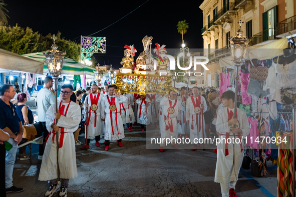 Members of the confraternity are carrying the statue of the Three Saints of Bisceglie during the procession through the town centre, in Bisc...