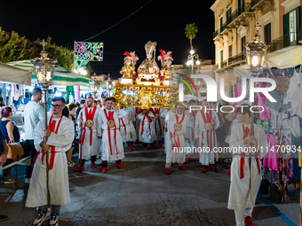 Members of the confraternity are carrying the statue of the Three Saints of Bisceglie during the procession through the town centre, in Bisc...