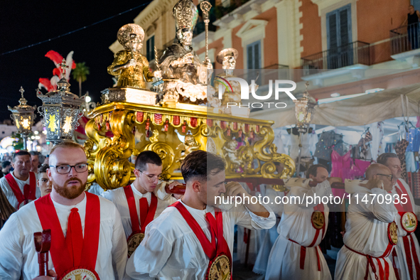 Members of the confraternity are carrying the statue of the Three Saints of Bisceglie during the procession through the town centre, in Bisc...