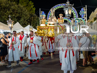 Members of the confraternity are carrying the statue of the Three Saints of Bisceglie during the procession through the town centre, in Bisc...