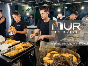 A boy is frying panzerotti for sale during the patronal feast of the Three Saints of Bisceglie, in Bisceglie, on August 11, 2024. Bisceglie...