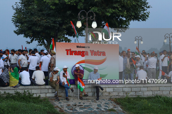 People are sitting on the banks of Dal Lake as they are taking part in the Tiranga Rally ahead of India's Independence Day celebrations in S...