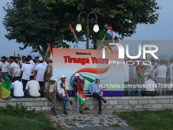 People are sitting on the banks of Dal Lake as they are taking part in the Tiranga Rally ahead of India's Independence Day celebrations in S...