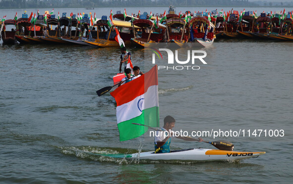 A man is riding a kayak as he takes part in the Tiranga Rally ahead of India's Independence Day celebrations in Srinagar, Jammu and Kashmir,...