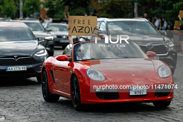 A demonstrator is holding a placard in a convertible during the Don't Be Silent. Captivity Kills! rally to support Ukrainian prisoners of wa...