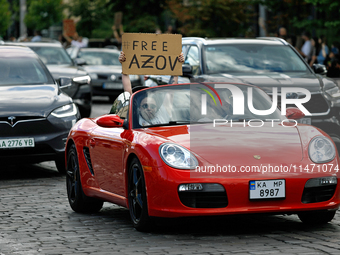 A demonstrator is holding a placard in a convertible during the Don't Be Silent. Captivity Kills! rally to support Ukrainian prisoners of wa...