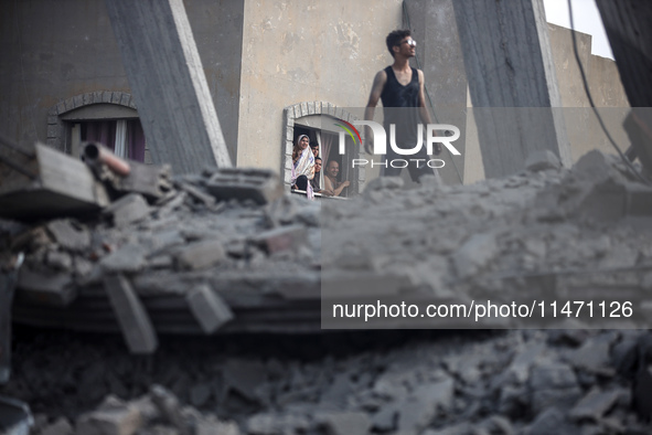 Palestinians are looking at a damaged house after an Israeli airstrike in Nuseirat, central Gaza Strip, on August 12, 2024, amid the ongoing...