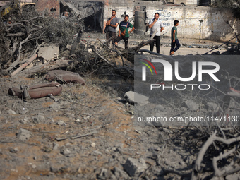 Palestinians are assessing the damage following an Israeli strike in the Nuseirat refugee camp in the central Gaza Strip on August 12, 2024,...