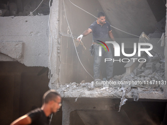 Palestinians are assessing the damage following an Israeli strike in the Nuseirat refugee camp in the central Gaza Strip on August 12, 2024,...