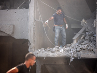 Palestinians are assessing the damage following an Israeli strike in the Nuseirat refugee camp in the central Gaza Strip on August 12, 2024,...