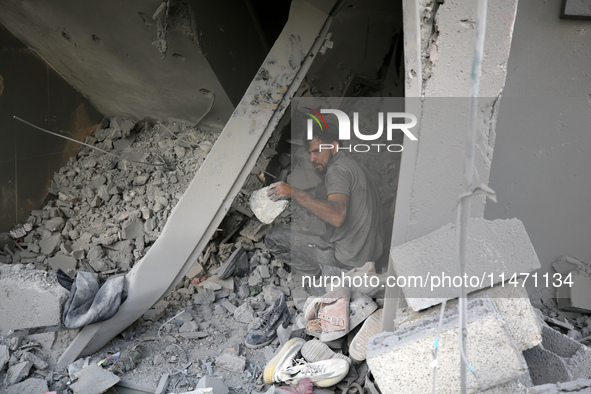 Palestinians are removing rubble from a destroyed building after an Israeli airstrike in Nuseirat, central Gaza Strip, on August 12, 2024, a...