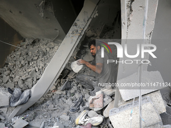 Palestinians are removing rubble from a destroyed building after an Israeli airstrike in Nuseirat, central Gaza Strip, on August 12, 2024, a...