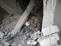 Palestinians are removing rubble from a destroyed building after an Israeli airstrike in Nuseirat, central Gaza Strip, on August 12, 2024, a...