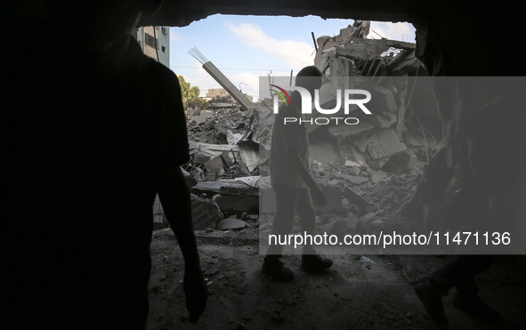 Palestinians are assessing the damage following an Israeli strike in the Nuseirat refugee camp in the central Gaza Strip on August 12, 2024,...