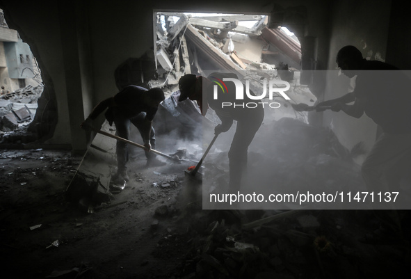 Palestinians are removing rubble from a destroyed building after an Israeli airstrike in Nuseirat, central Gaza Strip, on August 12, 2024, a...