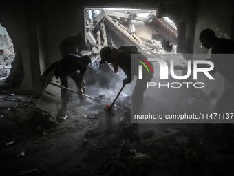 Palestinians are removing rubble from a destroyed building after an Israeli airstrike in Nuseirat, central Gaza Strip, on August 12, 2024, a...