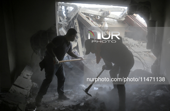 Palestinians are removing rubble from a destroyed building after an Israeli airstrike in Nuseirat, central Gaza Strip, on August 12, 2024, a...