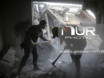 Palestinians are removing rubble from a destroyed building after an Israeli airstrike in Nuseirat, central Gaza Strip, on August 12, 2024, a...