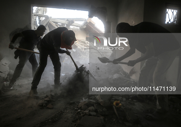 Palestinians are removing rubble from a destroyed building after an Israeli airstrike in Nuseirat, central Gaza Strip, on August 12, 2024, a...