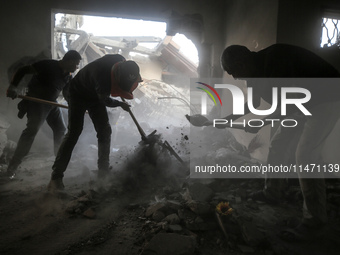 Palestinians are removing rubble from a destroyed building after an Israeli airstrike in Nuseirat, central Gaza Strip, on August 12, 2024, a...