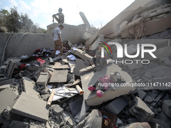 Palestinians are assessing the damage following an Israeli strike in the Nuseirat refugee camp in the central Gaza Strip on August 12, 2024,...