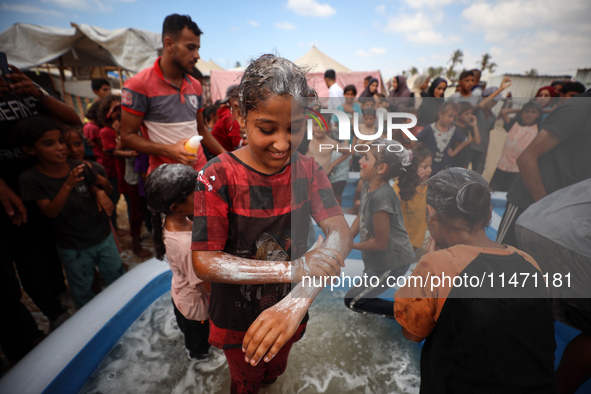 Palestinian children are playing with water and soap to cool themselves down during a heatwave at a temporary camp for the internally displa...