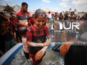 Palestinian children are playing with water and soap to cool themselves down during a heatwave at a temporary camp for the internally displa...