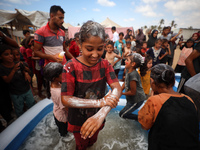 Palestinian children are playing with water and soap to cool themselves down during a heatwave at a temporary camp for the internally displa...